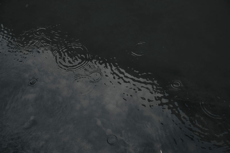 Raindrops forming concentric rings on the surface of dark, still water