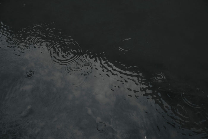 Raindrops forming concentric rings on the surface of dark, still water